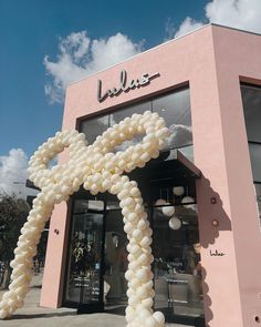 an outside view of a store with balloons in the air