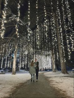 two people walking down a path covered in lights