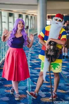 a man and woman in costumes standing on a blue carpeted floor, one holding a dog