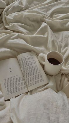 an open book and cup of coffee on a bed