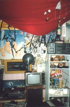 a room filled with lots of clutter next to a red canopy over a tv