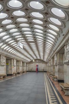 an empty train station with benches and round windows on the ceiling is seen in this image