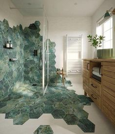 a bathroom with green tiles on the floor and walls, along with a wooden cabinet