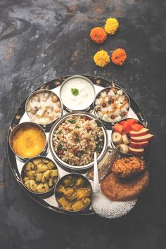 a plate full of different types of food on top of a black surface with flowers