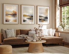 a living room with couches and paintings on the wall above them in front of a window