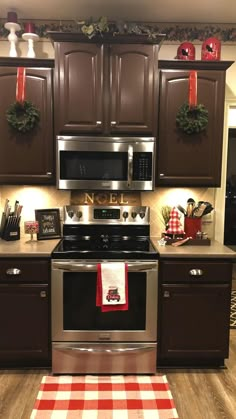 a kitchen decorated for christmas with brown cabinets and silver stove top oven, red checkered tablecloth on the floor