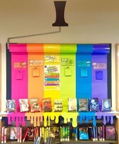 there are many books on the shelves with rainbow paint dripping from them, and an upside down book shelf in front of it