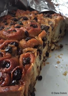 a piece of cake sitting on top of a white plate covered in tin foil and raisins