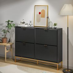 a black cabinet with two drawers and a lamp on the side table next to it