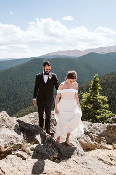 a bride and groom walking on top of a mountain