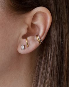 a woman's ear with two small gold hoops