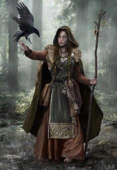 a woman dressed in medieval clothing holding a crow