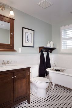 a white bath tub sitting next to a toilet under a bathroom mirror on top of a wooden cabinet