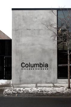 the columbia college sign is next to a tree in front of a building on a snowy day