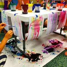 children are painting on the table with their hands and legs in front of them, while others look on