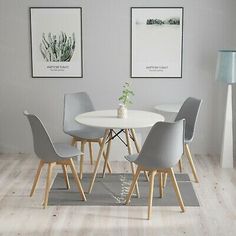 a white table with four grey chairs in front of two framed pictures on the wall