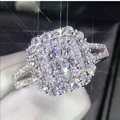 a diamond ring is being held up by someone's hand in front of a display case