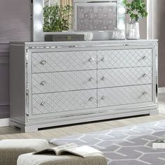 a white dresser sitting in front of a mirror on top of a wooden floor next to a gray rug