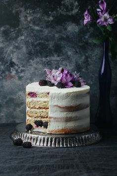 a cake with white frosting and purple flowers on top