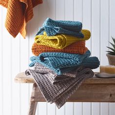 a stack of folded towels sitting on top of a wooden bench next to a potted plant