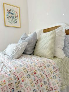 a bed with many pillows on top of it and a painting above the headboard