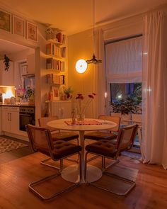 a dining room table and chairs in front of an open kitchen door with the lights on