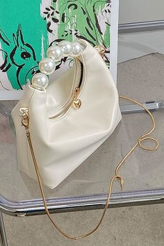 This petite yet striking purse offers a chic modern look with pearl details to elevate your outfit. Crafted from soft vegan leather, the purse features a top handle and a removable shoulder strap. The perfect companion for special occasions, this pearl handle purse will add a touch of refinement to any ensemble. Elegant Party Shoulder Bag With Zipper Closure, Chic Pearl Embellished Shoulder Bag, Cream Crossbody Shoulder Bag With Pearl Handle, Trendy Clutch Bag With Pearl Handle, Crossbody Evening Bag With Pearl Handle, Elegant Crossbody Evening Bag With Pearl Handle, Chic Everyday Pearl Shoulder Bag, Elegant Pearl Handle Crossbody Evening Bag, Chic Beige Evening Bag With Pearl Handle