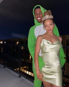 a man and woman dressed in costumes posing for a photo on a balcony at night