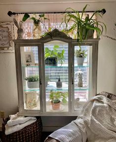 an open window with plants in it next to a wicker basket on the floor