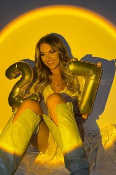 a woman sitting on top of a bed in yellow boots