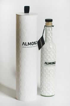 an empty white bottle next to a cardboard box on a white background with the word almond printed on it