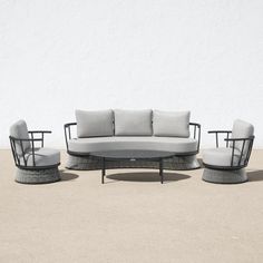 an outdoor sofa set with cushions and two chairs on concrete ground next to white wall