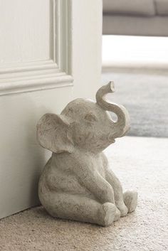 an elephant figurine sitting on the floor next to a door way with its trunk sticking out