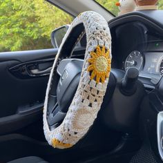 the steering wheel cover is crocheted with yellow and white flowers on it's center