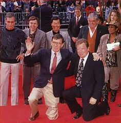 a group of men standing on top of a red carpet next to each other in front of a crowd