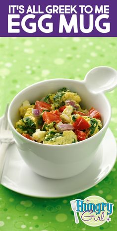 an egg salad with spinach and tomatoes in a white bowl on a green table