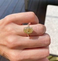 a woman's hand with a yellow diamond ring on it