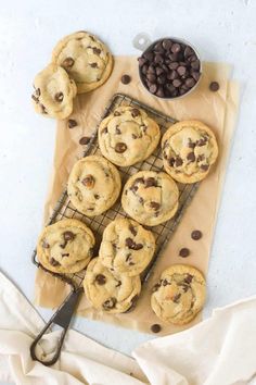 chocolate chip cookies cooling on a wire rack next to a bowl of chocolate chips and a spoon