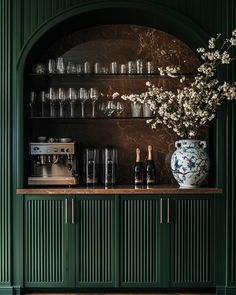 a green cabinet with wine glasses and bottles on it