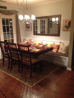 a dinning room table and bench in front of a window with the lights on