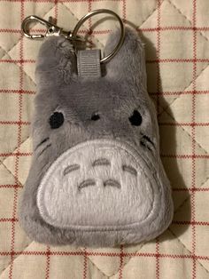 a gray stuffed animal keychain with a face drawn on it's side