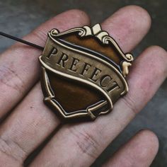 a hand holding a small metal object with the word perfect in it's center