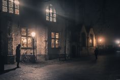 a person standing in front of a building on a street at night with the lights on