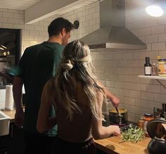 two people in a kitchen preparing food on the stove top and cooking with utensils