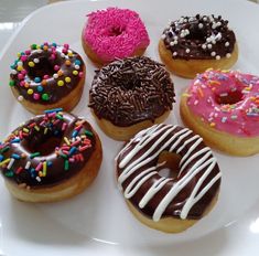 a white plate topped with donuts covered in frosting and sprinkles