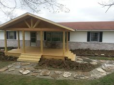 a wooden porch with steps leading up to it and a covered patio in the background