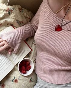 a woman is reading a book and eating strawberries