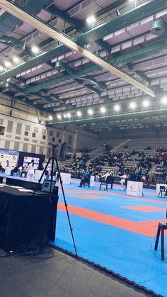 an indoor wrestling ring with people on the sidelines and in the middle of it