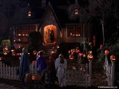 a group of people standing in front of a house decorated for halloween