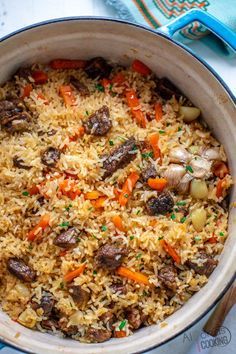 a pot filled with rice and vegetables on top of a blue cloth next to a fork